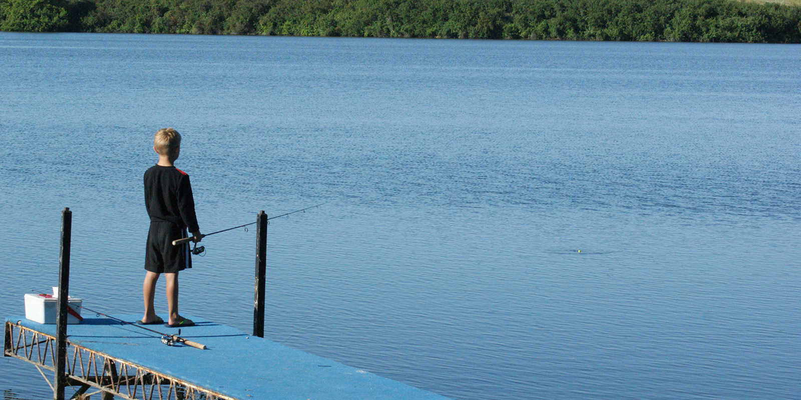 Gavin fishing from blue dock with yellow bobber